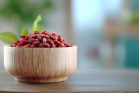 Dried goji berries in wooden bowl on kitchen counter with fresh green leaves for healthy superfood nutrition and wellness lifestyle.
