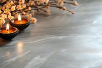 Lit candles in black holders with dried golden flowers on marble surface, creating warm ambiance for home decor, wellness, and spa design projects.