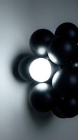 Cluster of black spheres with one glowing white orb in center against gray background, creating contrast and depth for concepts of leadership, innovation, uniqueness, and standing out.