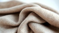 Soft beige linen fabric with natural texture draped in elegant folds, perfect for home decor, fashion design, and textile projects.
