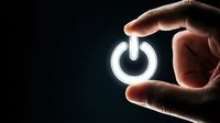 Hand holding glowing power button symbol against dark background, representing energy control, technology startup, and digital activation for web and app design projects.