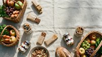 Healthy organic food ingredients in rustic baskets and glass jars arranged on white marble surface for cooking and meal preparation projects.