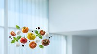 Fresh organic tomatoes and basil leaves floating in modern kitchen interior for healthy cooking and nutrition concepts.