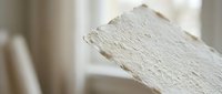 Handmade white paper sheet with rough deckled edges on soft neutral background for crafting and artistic projects.