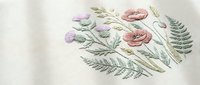 Delicate floral embroidery on cream fabric featuring pink roses, purple flowers and green ferns in vintage botanical style for textile and craft projects.