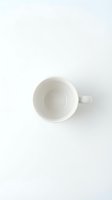 Empty white ceramic mug with handle on clean background, overhead view. Isolated cup ready for mockup designs, branding, product presentation, and commercial use.
