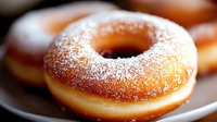 Fresh baked sugar dusted donut on white plate with soft focus background, golden brown pastry with powdered coating and classic round shape.