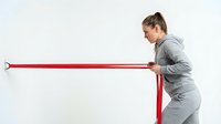 Young athletic woman in gray sportswear doing resistance band exercise training workout on white background isolated for fitness design.