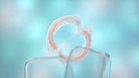Transparent glass cup with pink water splash frozen in mid-air against soft blue blurred background, suitable for beverage, refreshment, and product advertising designs.