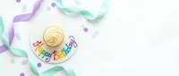Festive birthday cupcake with colorful Happy Birthday topper, pastel ribbons, and confetti on white background, perfect for celebration cards.