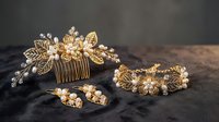 Elegant gold wedding hair accessories set with floral design, pearls and crystals on dark wooden background for bridal styling and special occasions.