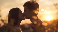 Romantic couple silhouette kissing at golden sunset with warm bokeh lights creating intimate atmosphere for love and relationship concepts.