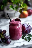 Fresh purple smoothie with plums and grapes in mason jar on marble background, garnished with fresh fruits. Natural light food photography.