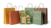 Colorful kraft paper shopping bags with SALE letters arranged on white background, perfect for retail promotions and eco-friendly store concepts.