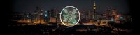 Young adult male of mixed ethnicity wearing casual attire, holding illuminated circuit board globe against night cityscape backdrop, representing technology innovation, digital connectivity, and smart city solutions.