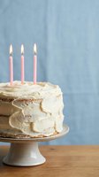 Birthday cake with pink candles on ceramic stand against blue background for celebration party dessert.