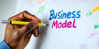 African American businessman writing business model text on whiteboard with colorful markers during strategic planning meeting or presentation.