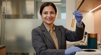 Professional Hispanic female scientist in business suit holding test tube sample in modern laboratory for research and development work.