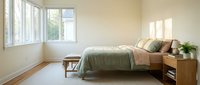 Minimalist bedroom interior with natural light streaming through large windows, featuring wooden furniture and neutral bedding for modern home design.