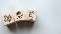 Wooden blocks with mental health symbols including brain, hand and human head icons representing psychology, wellness and mindfulness concepts.