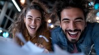 Young diverse couple laughing together at night, showing genuine joy and happiness. Candid lifestyle moment with bokeh lights and natural expressions.