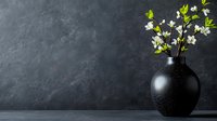 Minimalist spring composition with white cherry blossom branches in black ceramic vase against dark textured wall background, moody atmospheric lighting.