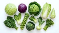 Fresh green vegetables collection including cabbage, kale, broccoli, Brussels sprouts, bok choy and peas isolated on white background for healthy cooking.