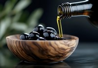 Olive oil pouring from bottle into wooden bowl filled with fresh black olives, dramatic lighting on dark background creates gourmet food atmosphere.