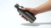 Person holding black stainless steel water bottle isolated on white background, suitable for product marketing and lifestyle advertising.