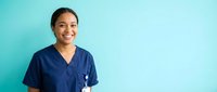 Happy young Hispanic female nurse in blue scrubs smiling confidently against turquoise background for healthcare and medical profession concepts.