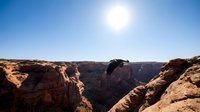 Vast desert canyon landscape with towering red rock formations and clear blue sky, suitable for travel, nature, and background design projects.