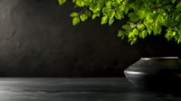 Minimalist dark stone table with green fresh leaves and black ceramic bowl against dramatic black background, creating zen atmosphere for spa and wellness.