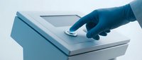 Medical professional in blue gloves operating modern digital equipment touchscreen interface for healthcare technology and patient care applications.