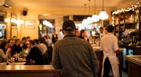 Busy restaurant interior with customers dining and staff working, warm ambient lighting creates cozy atmosphere for hospitality and food service business.