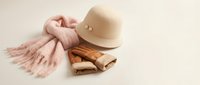 Cozy autumn fashion accessories with knitted pink scarf, beige felt hat and brown leather boots arranged on neutral background for seasonal style concepts.