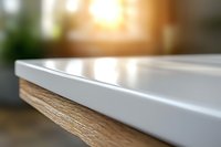 Close up view of white wooden table edge with soft blurred background and warm sunlight, modern minimalist furniture detail for interior design concepts.