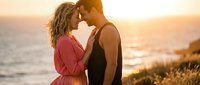 Young couple embracing intimately at golden hour sunset by ocean shore, romantic moment with warm lighting for wedding, love and relationship concepts.