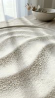 Zen sand garden with raked wave patterns in shallow bowl, natural light from window, minimalist spa decor with dried botanicals, meditation and relaxation concept.