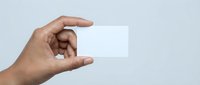 Hand holding blank white business card mockup against gray background for branding and corporate identity design projects.