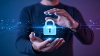Businessman protecting digital padlock icon with hands representing cybersecurity, data protection and privacy concepts in technology environment.