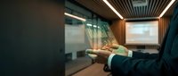 Businessman holding tablet with holographic data visualization in modern office conference room with projection screen.
