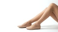 Elegant female legs in nude ballet flats on white background showcasing smooth skin and graceful posture for fashion and beauty concepts.