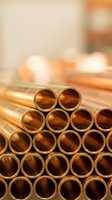 Stack of shiny copper pipes arranged in rows with warm industrial background for construction and plumbing projects.