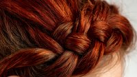 Close-up of braided auburn hair showing intricate plait detail with rich copper and mahogany tones, highlighting professional hairstyling technique.