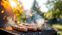 Grilled sausages on barbecue grill with rising smoke and flying sparks in golden sunset light, outdoor cooking scene with bokeh effect in background.