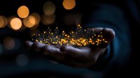 Magical glowing golden particles floating above open palm against dark background with bokeh lights creating mystical atmospheric scene.