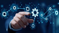 Businessman pointing at glowing gear network on dark background with bokeh effect, representing digital transformation and business automation process.