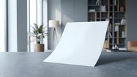 Blank white paper sheet on modern office desk with natural lighting and contemporary workspace background for mockup presentations.