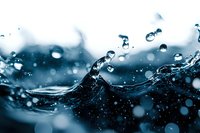 Dynamic water splash with droplets and bubbles creating fluid motion against blue background for refreshing beverage and hydration concepts.