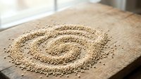 Spiral pattern made from small beige pellets arranged on wooden surface near window, suitable for abstract backgrounds and creative design projects.